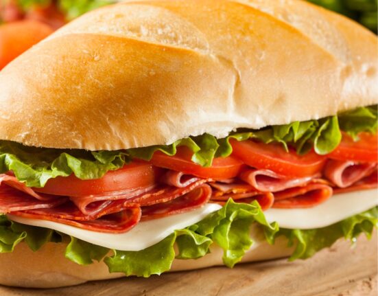 Two Italian Sub Sandwiches on a wooden cutting board