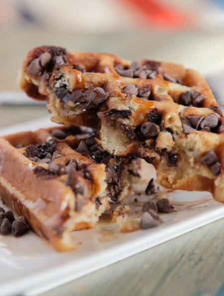 A homemade chocolate chip waffle cut in half on a plate
