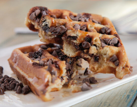 A homemade chocolate chip waffle cut in half on a plate