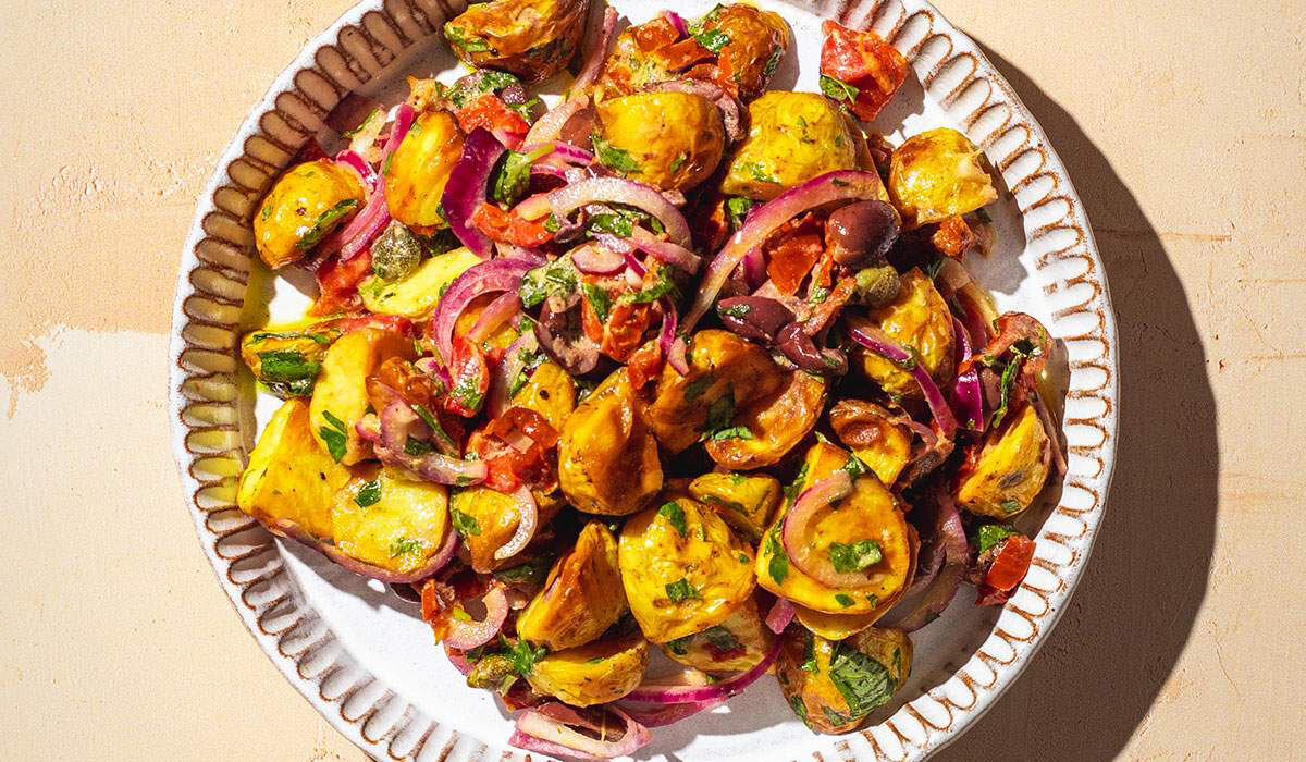 Italian potato salad on a serving plate in the sun.
