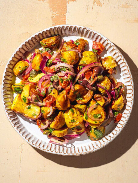 Italian potato salad on a serving plate in the sun.
