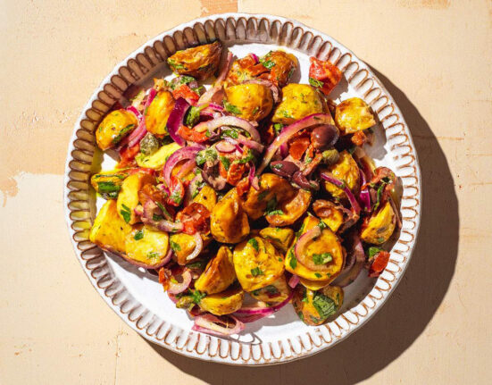 Italian potato salad on a serving plate in the sun.