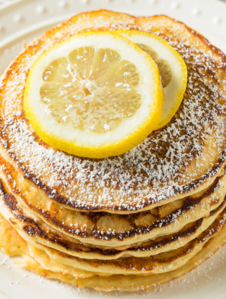 Overhead image of lemon ricotta pancakes with slices of lemon on top
