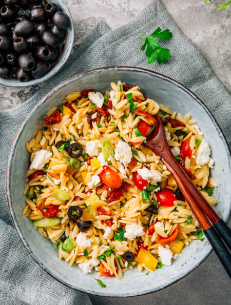 Overhead image of Orzo Salad in a bowl with serving spoons