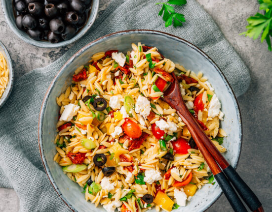 Overhead image of Orzo Salad in a bowl with serving spoons