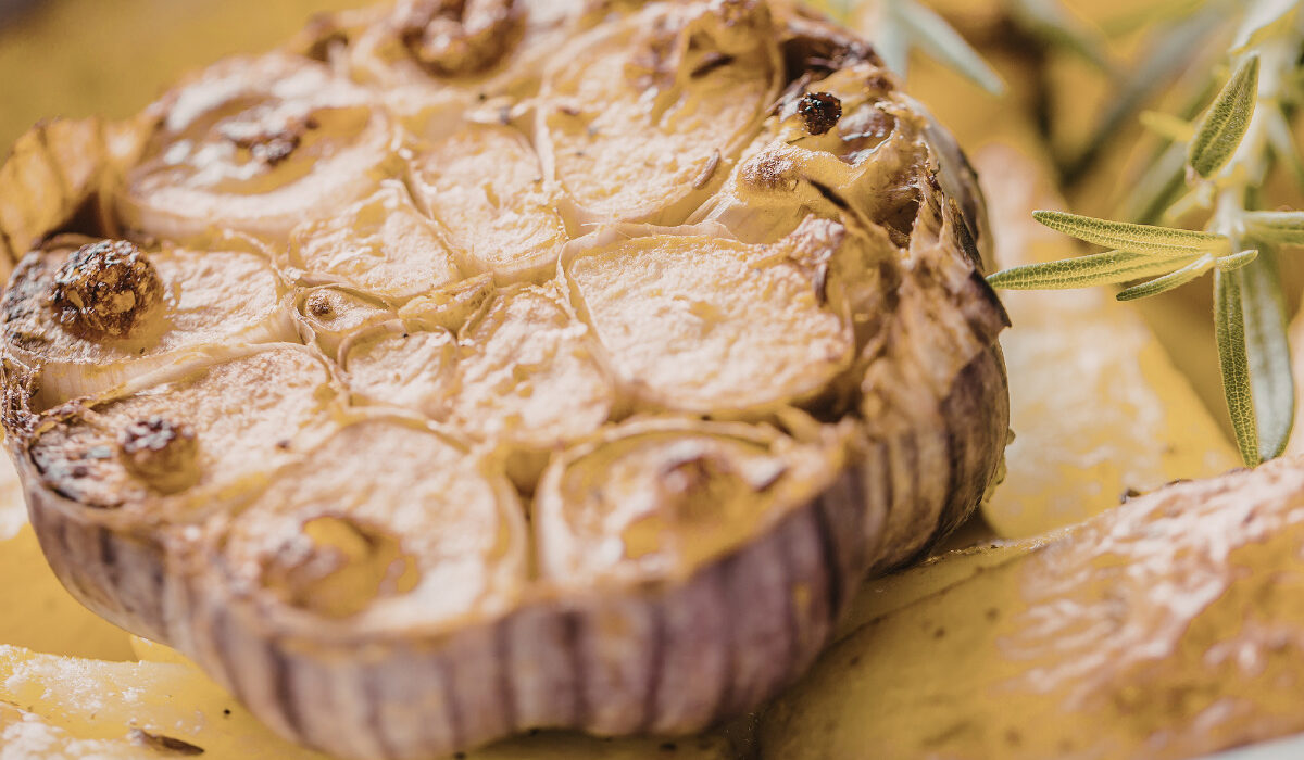 Close up image of a head of roasted garlic on a plate