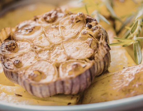 Close up image of a head of roasted garlic on a plate