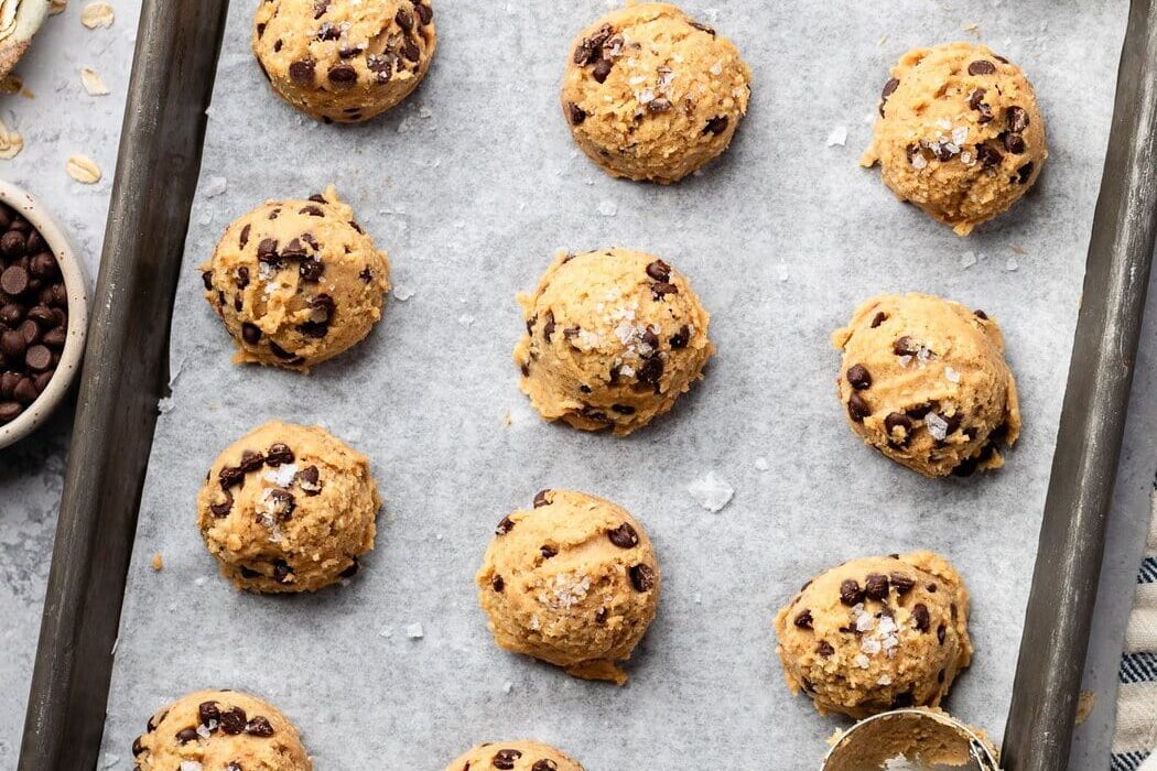 Overhead view of a sheet pan lined with parchment paper topped with cookie dough bites.