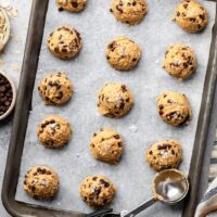 Overhead view of a sheet pan lined with parchment paper topped with cookie dough bites.