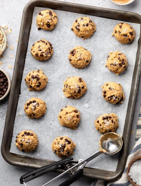 Overhead view of a sheet pan lined with parchment paper topped with cookie dough bites.