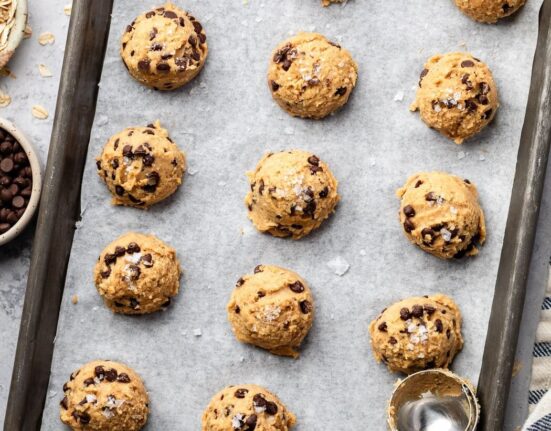 Overhead view of a sheet pan lined with parchment paper topped with cookie dough bites.