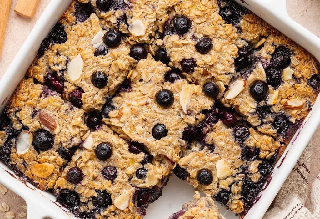 Overhead view of a white baking dish filled with blueberry baked oatmeal cut into 9 squares.