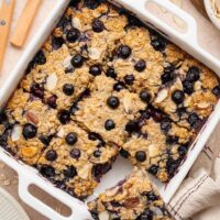Overhead view of a white baking dish filled with blueberry baked oatmeal cut into 9 squares.