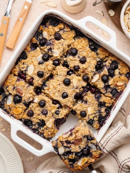 Overhead view of a white baking dish filled with blueberry baked oatmeal cut into 9 squares.