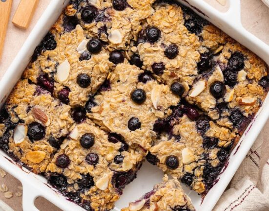 Overhead view of a white baking dish filled with blueberry baked oatmeal cut into 9 squares.
