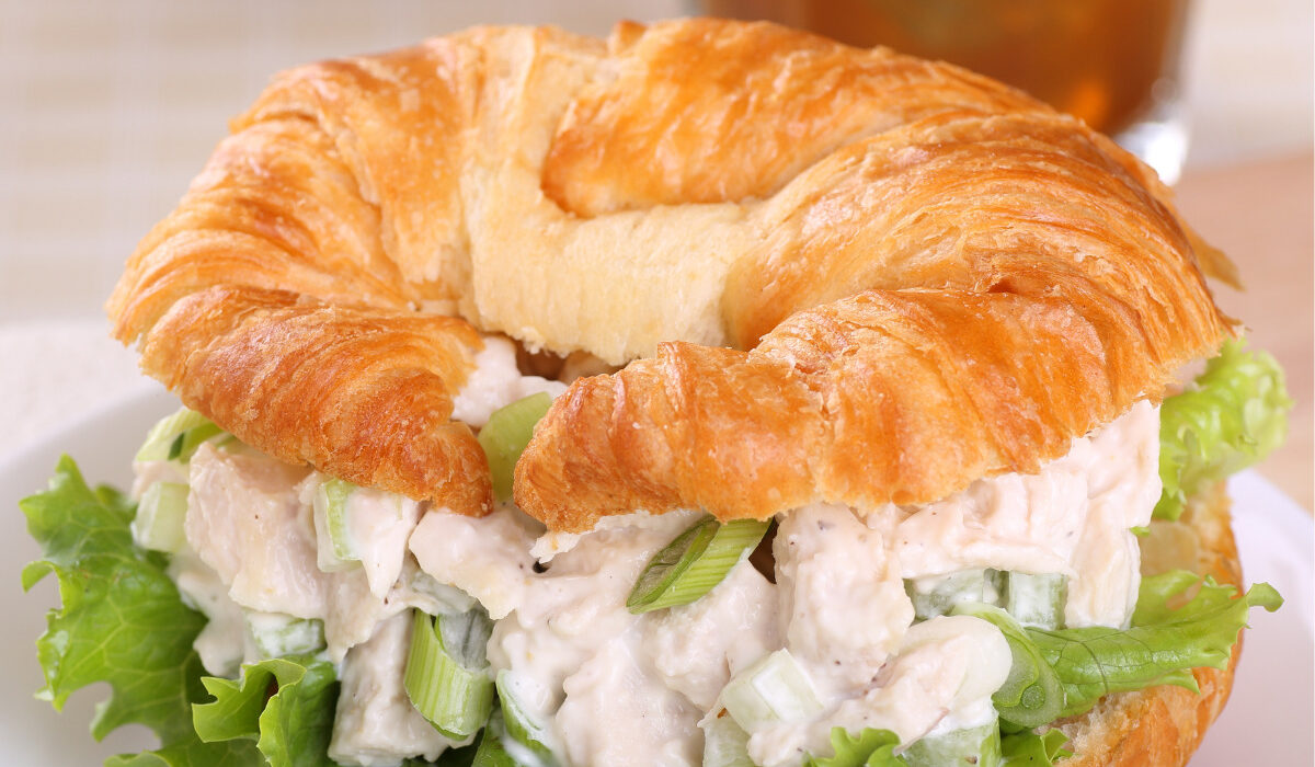 A chicken salad sandwich on a croissant with lettuce