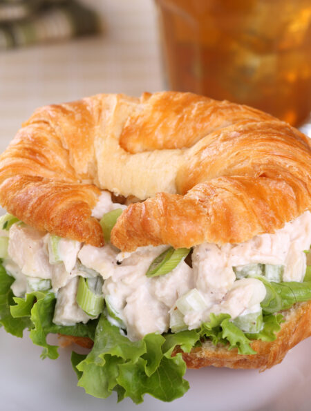 A chicken salad sandwich on a croissant with lettuce