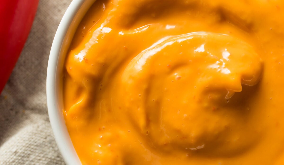 overhead image of chipotle aioli in a white bowl with a red pepper next to it