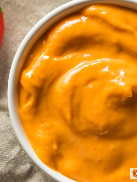 overhead image of chipotle aioli in a white bowl with a red pepper next to it