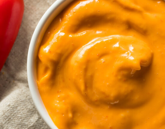 overhead image of chipotle aioli in a white bowl with a red pepper next to it
