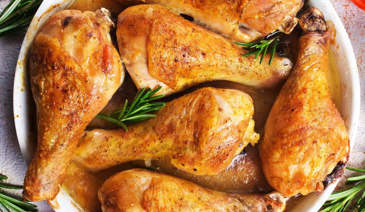 overhead image of crispy baked chicken legs in a white dish with herbs