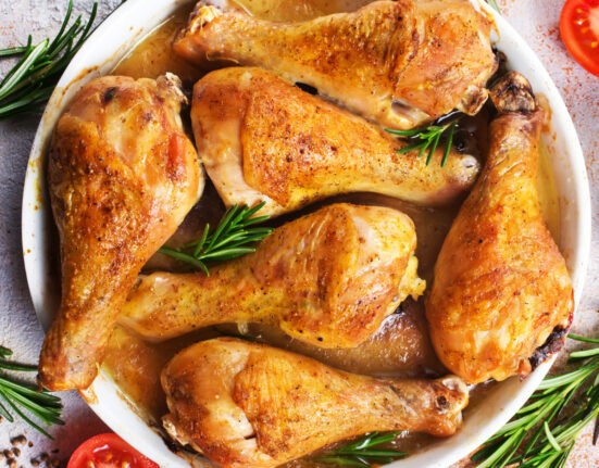 overhead image of crispy baked chicken legs in a white dish with herbs