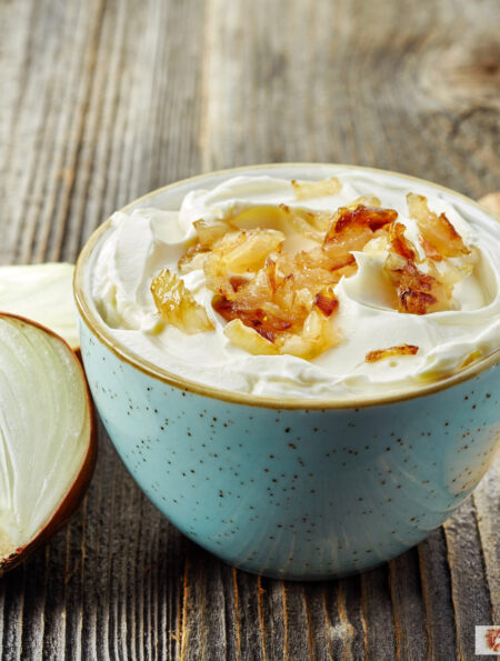 French Onion Dip in a blue bowl with an onion next to it