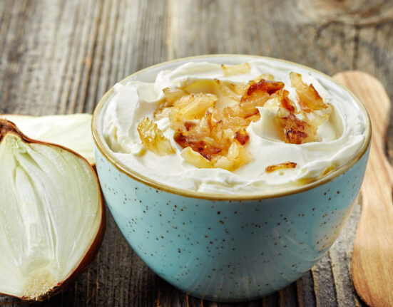 French Onion Dip in a blue bowl with an onion next to it