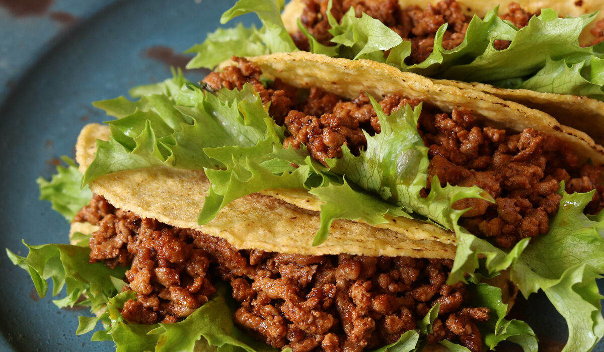 Three crunchy tacos with Instant Pot Taco Meat and lettuce on a blue plate