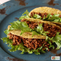 Three crunchy tacos with Instant Pot Taco Meat and lettuce on a blue plate
