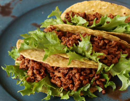 Three crunchy tacos with Instant Pot Taco Meat and lettuce on a blue plate