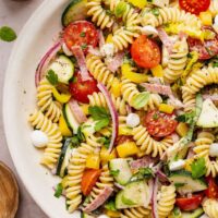 Overhead view of a colorful Zesty Italian Pasta Salad topped with fresh herbs and black pepper.