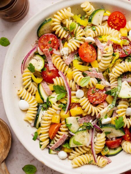 Overhead view of a colorful Zesty Italian Pasta Salad topped with fresh herbs and black pepper.