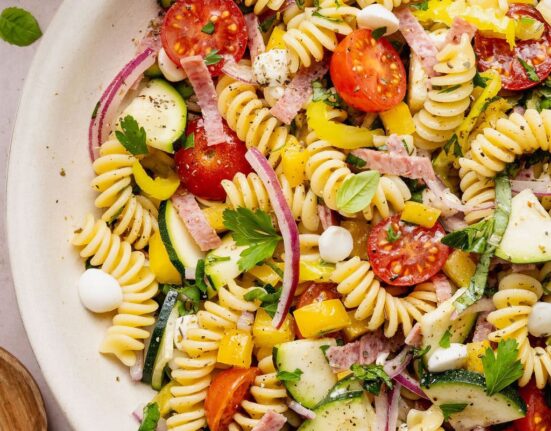 Overhead view of a colorful Zesty Italian Pasta Salad topped with fresh herbs and black pepper.
