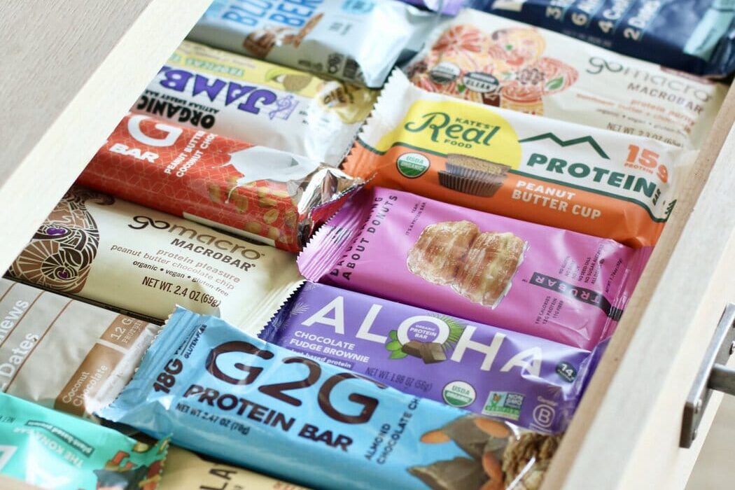 An open slide-out kitchen draw filled with rows of protein bars.