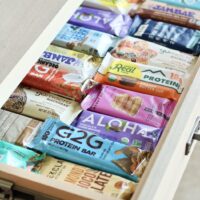 An open slide-out kitchen draw filled with rows of protein bars.