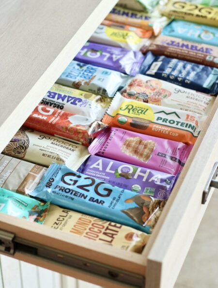 An open slide-out kitchen draw filled with rows of protein bars.