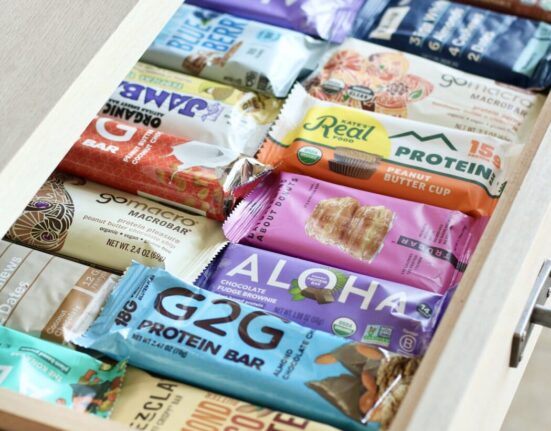 An open slide-out kitchen draw filled with rows of protein bars.