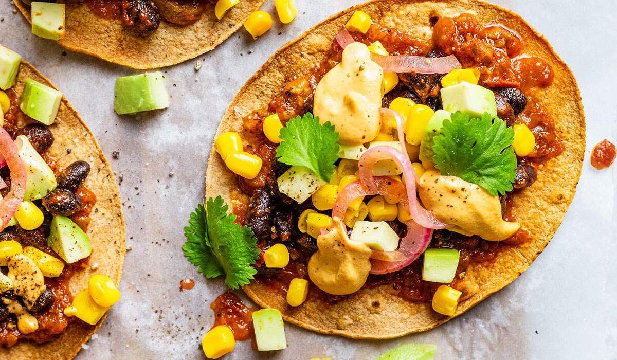 Vegan tostadas with black beans, sweetcorn, salsa, pickled onions, cilantro and vegan nacho cheese sauce.