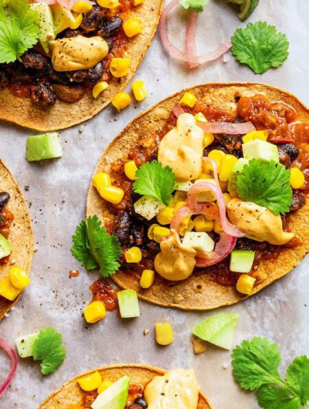 Vegan tostadas with black beans, sweetcorn, salsa, pickled onions, cilantro and vegan nacho cheese sauce.
