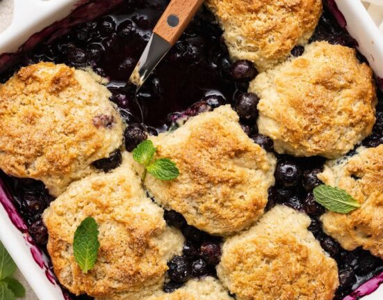 Overhead view of a baking dish filled with Blueberry Cobbler garnished with fresh mint leaves.