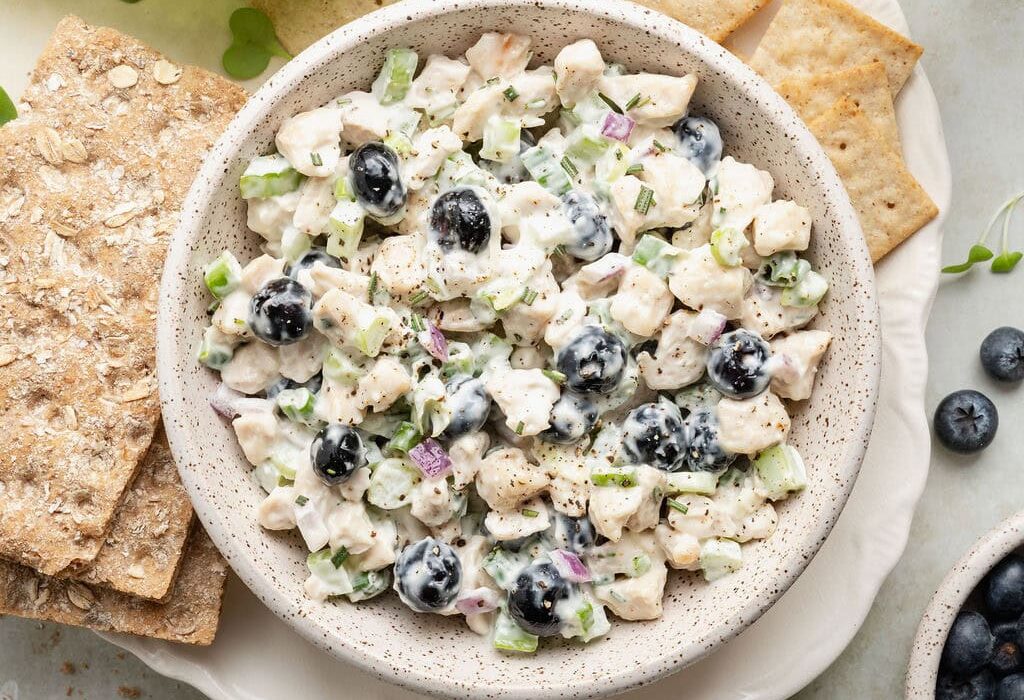 Overhead view of a bowl of Blueberry Chicken Salad surrounded by crackers.