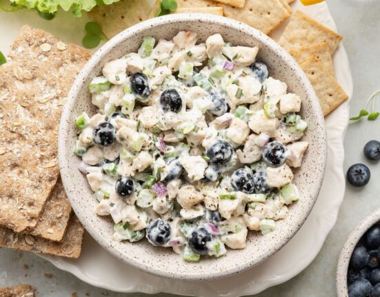 Overhead view of a bowl of Blueberry Chicken Salad surrounded by crackers.