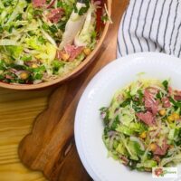 A bowl of la scala salad next to the mixing bowl of prepared salad