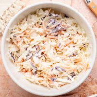 Overhead view of a white bowl filled with fresh coleslaw.