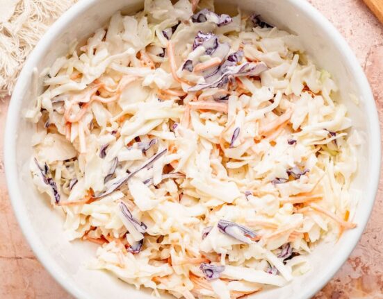Overhead view of a white bowl filled with fresh coleslaw.