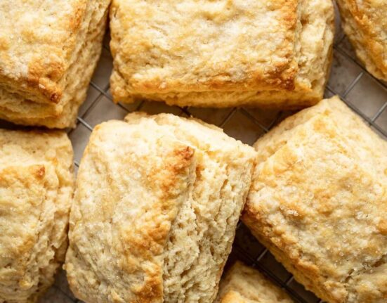 Close up view of sweet cream biscuits on a wire cooling rack showing the flakey layers
