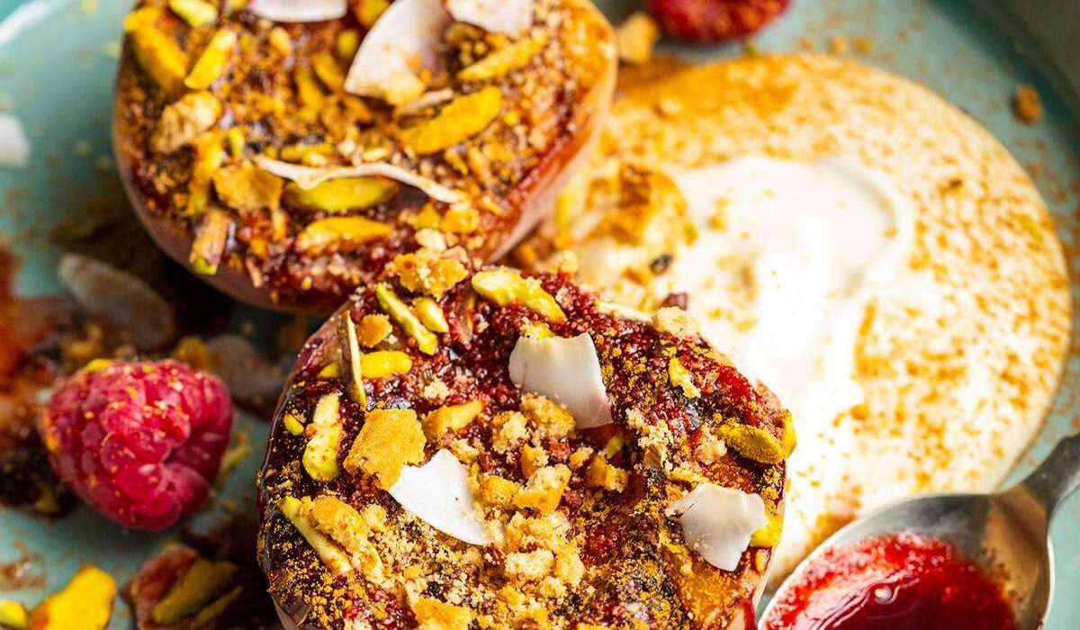 Grilled balsamic peaches with coconut yogurt and raspberry coulis on a dessert plate.