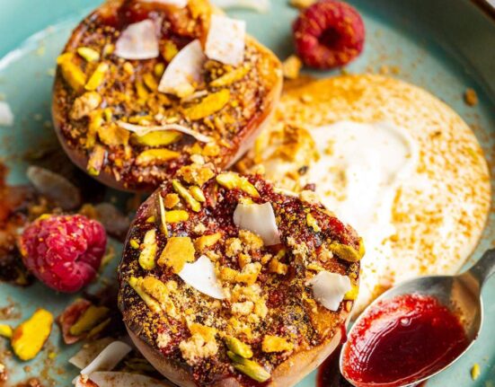 Grilled balsamic peaches with coconut yogurt and raspberry coulis on a dessert plate.